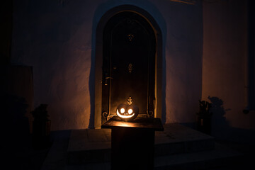 Front door to a house decorated with Halloween pumpkin. Halloween pumpkin on a door steep at night