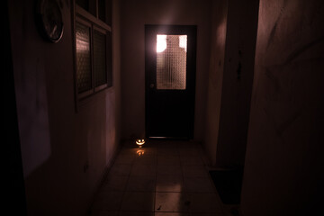 Halloween concept. Creepy silhouette in the dark corridor with pumpkin head. Toned light with fog on background.
