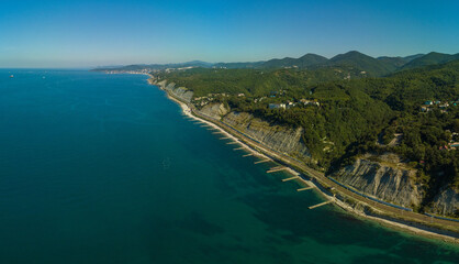 over the Black Sea beaches near the green Caucasian mountains near the village of Dederkoy in the South of Russia. Concrete breakwaters along the edge of the sea and the port of Tuapse on the horizon