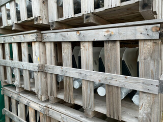 Wooden boxes with materials and pipes are stored in a warehouse with industrial equipment