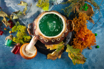 Top view on boiling green liquid in clay pot and autumn leaves, moss, toadstool web around....