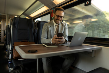 Formal wearing business man traveling to work by train.
Business man is working while traveling, using laptop, mobile phone, and taking notes.
Business man planning goals and meetings