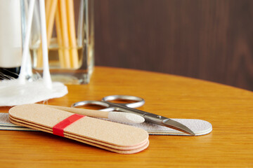 Naklejka premium Manicure tools, scissors, nail file, cotton swab on the wooden display