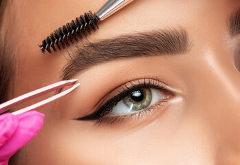 Makeup artist plucks eyebrows. Long-lasting styling of the eyebrows and color the eyebrows. Eyebrow...