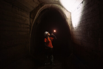 Obraz na płótnie Canvas Female digger with flashlight explores the tunnel