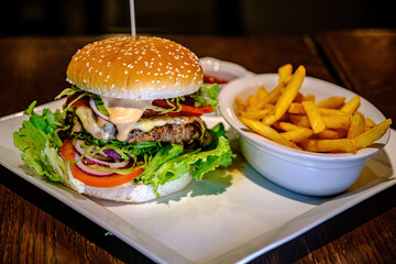 Delicious juicy burgers with beef, tomato, cheese, lettuce and french fries.