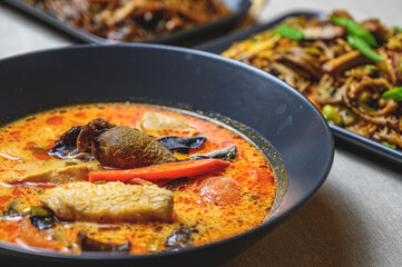 tom yum - spicy thai soup with chicken in a black bowl on the table, top view.