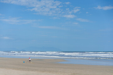 criança brincando sozinha em praia vazia 