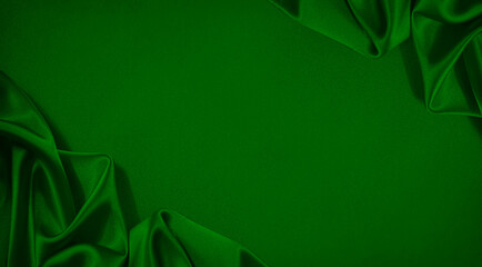 Green silk satin. Beautiful soft folds. Shiny fabric. Luxury background with space for design....