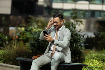 Business man on break, outside sitting in park using phone