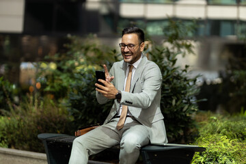 Business man on break, outside sitting in park using phone