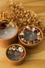 handmade aromatic candles with dried flowers above and on the side