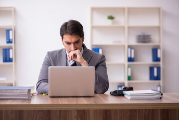 Young attractive male employee sitting at workplace