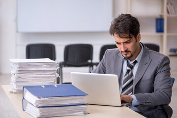 Fototapeta premium Young businessman employee and too much work in the office