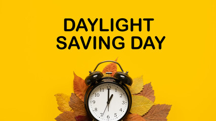 Daylight saving day. Fall Back. Black Alarm clock and autumn leaves and text Daylight saving day on...