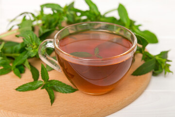 Cup of mint tea on table background. Green tea with fresh mint top view with copy space