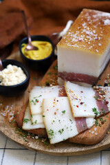 Fresh lard with meat layer on a wooden board with spices, mustard and horseradish. Delicious snack. Bacon.
