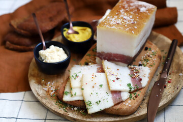 Fresh lard with meat layer on a wooden board with spices, mustard and horseradish. Delicious snack. Bacon.