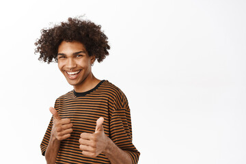 Close up portrait of happy young man showing thumbs up and praising, give compliments to you, good...