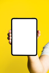 Digital tablet with white screen in man hand isolated on yellow background. Mobile application advertisement. Product placement copy space