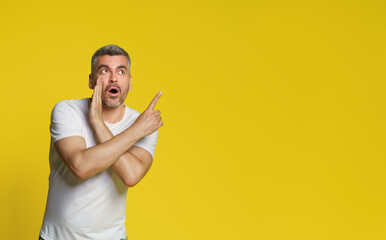 Gesturing sideways telling a secret handsome middle aged man cover his mouth with hand wearing...