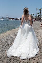 Obraz premium Bride wearing white wedding dress walking outdoor at sea.