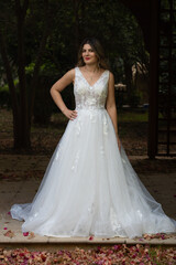 Obraz premium Pregnant happy smiling bride with white wedding dress posing outdoor