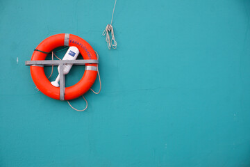 Reykjavik, Iceland - An orange life saving buoy hanging on a greenish-blue wall. Image has copy space. - obrazy, fototapety, plakaty