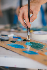 Artist mixes paints with a brush on a palette