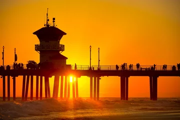Papier Peint photo autocollant Ville sur leau Silhouette d& 39 une jetée avec des gens marchant sous un ciel orange au coucher du soleil sur Huntington Beach, Californie