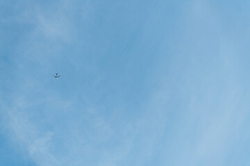 Low angle view of passenger airplane flying in clear blue sky with few cirrus clouds. Copy space for your text. Transportation theme.