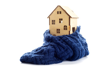 Wooden toy house is wrapped in a warm scarf isolated on white background