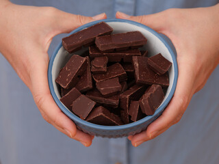 A woman holding a bowl of broken dark chocolate in her hands