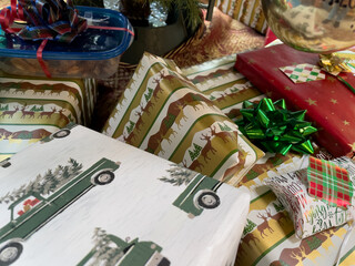 Fototapeta premium Wrapped Christmas presents with bows and tags stacked under the Christmas tree.