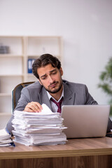 Naklejka premium Young male employee and too much work in the office