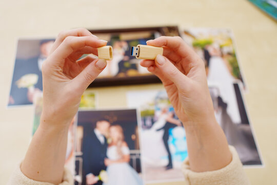 selective focus. printed wedding photos, wooden box and hands with flash drive