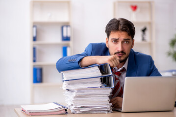 Young male employee and too much work in the office