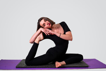 Joven mujer en bella postura estirando su cuerpo en su mat de yoga. Pilates y actividades saludables