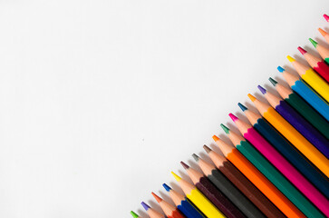 Lápices de colores alineados en diagonal, en fondo blanco. Fotografía con desenfoque selectivo....