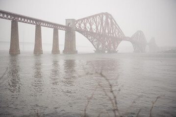 View of the George IV Bridge Rail Bridge from South Queensferry across the water of the Firth of Forth in an Winter day in Edinburgh, Scotland, UK, under low visibility due to the snow during a blizza