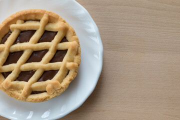 Crostata al cioccolato con piattino bianco su tavolo di legno