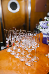 A lot, a row of empty transparent expensive wine glasses stands on a wooden table in a bar, cafe close-up.