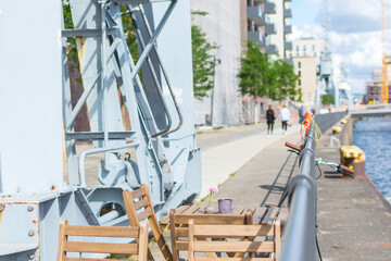 Naklejka premium Sunny cozy seat at a wooden cafe table on the shore of Baakenhafen in Hamburg. View of the new Baakenpark in the Hafencity.