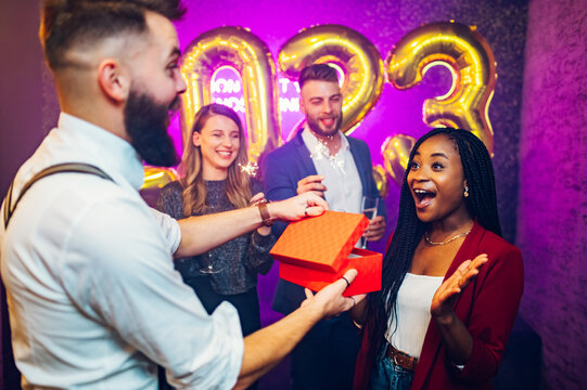 Multiracial couple exchanging gifts for birthday party or new years eve in the club