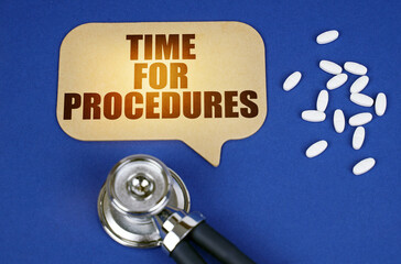 On the blue surface of the tablet, a stethoscope and a cardboard sign with the inscription - Time for procedures