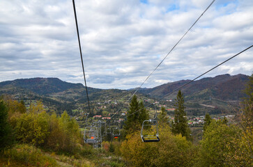 Empty сhairlift on a fall mountain slope with colorful trees. Elevator in the autumn season....