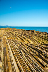 View on steeply-tilted layers of flysch on Atlantic coast at Zumaia at low tide, Basque Country, Spain