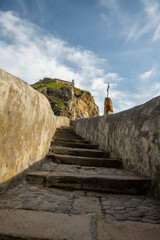 Stone footpath to famous landmark and film location in North of Spain, ocean islet with chapel San...