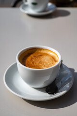 Small white cup of black arabica coffee served outdoor