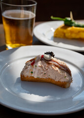 Sunny day in San Sebastián, typical food and drink in bars of Basque Country, pinchos or pinxtos, small slices of bread with different toppings and glass of beer, lunch in Spain